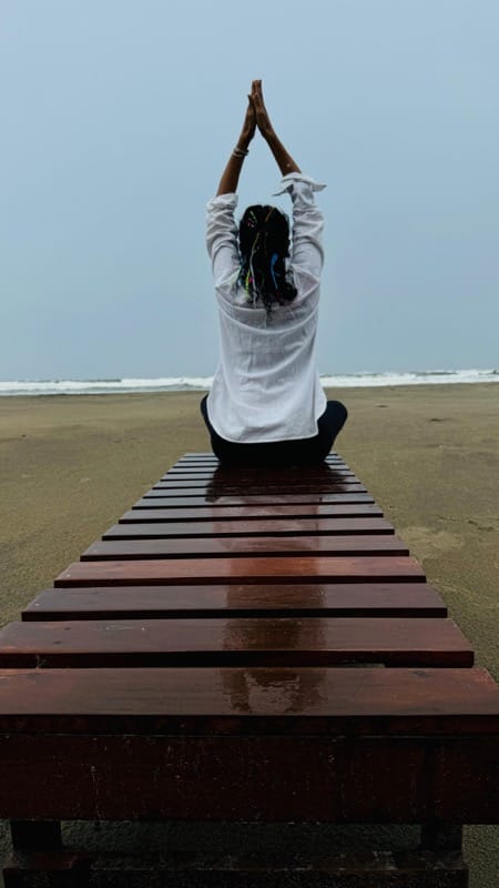 Student in meditative pose by the ocean