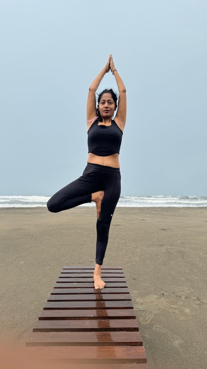 Yoga student in tree pose at the beach